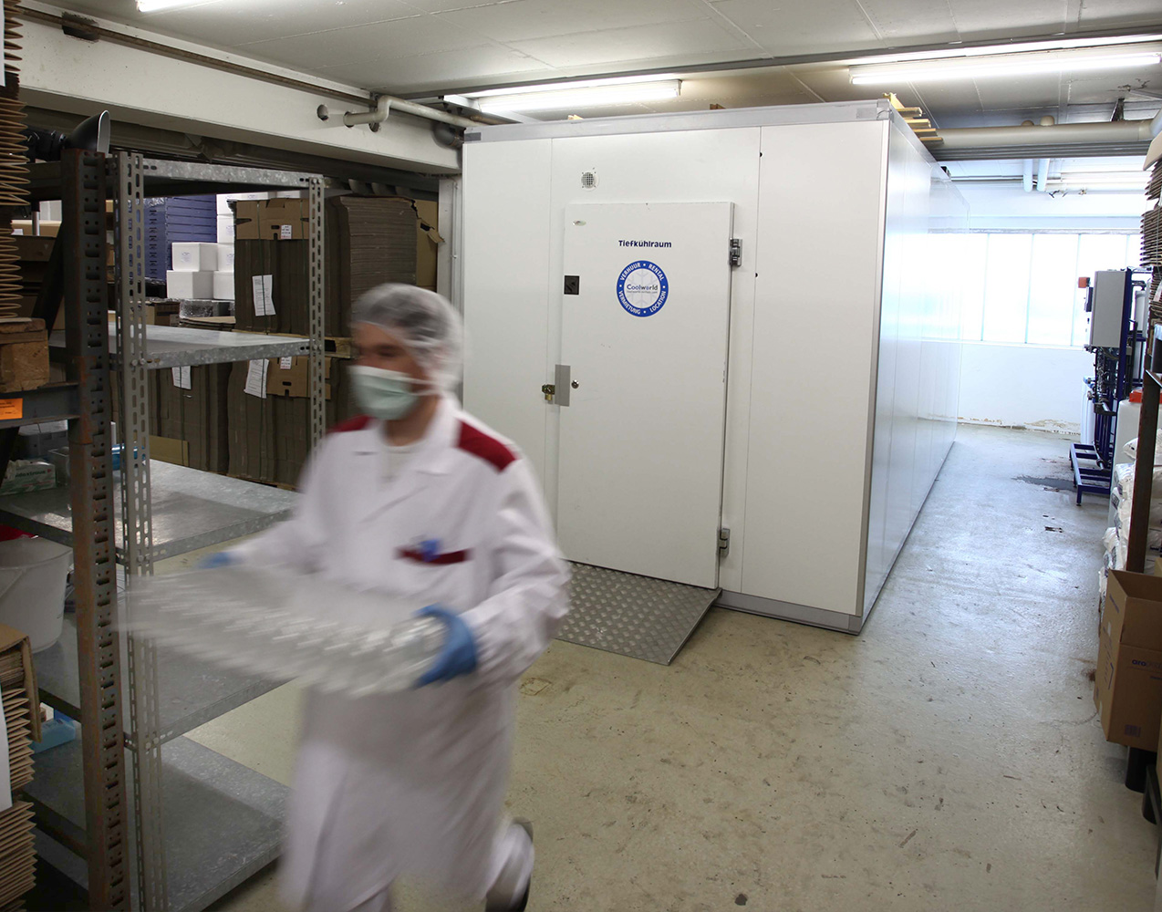 Mitarbeiter in Schutzkleidung vor Temperierzelle in Lebensmittelproduktion