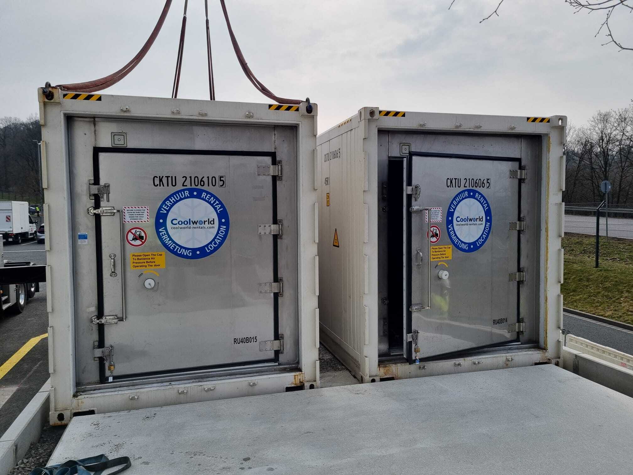 Zwei Coolworld Rentals Kühlcontainer mit geöffneten Türen werden per Kran auf einem Transportfahrzeug geliefert